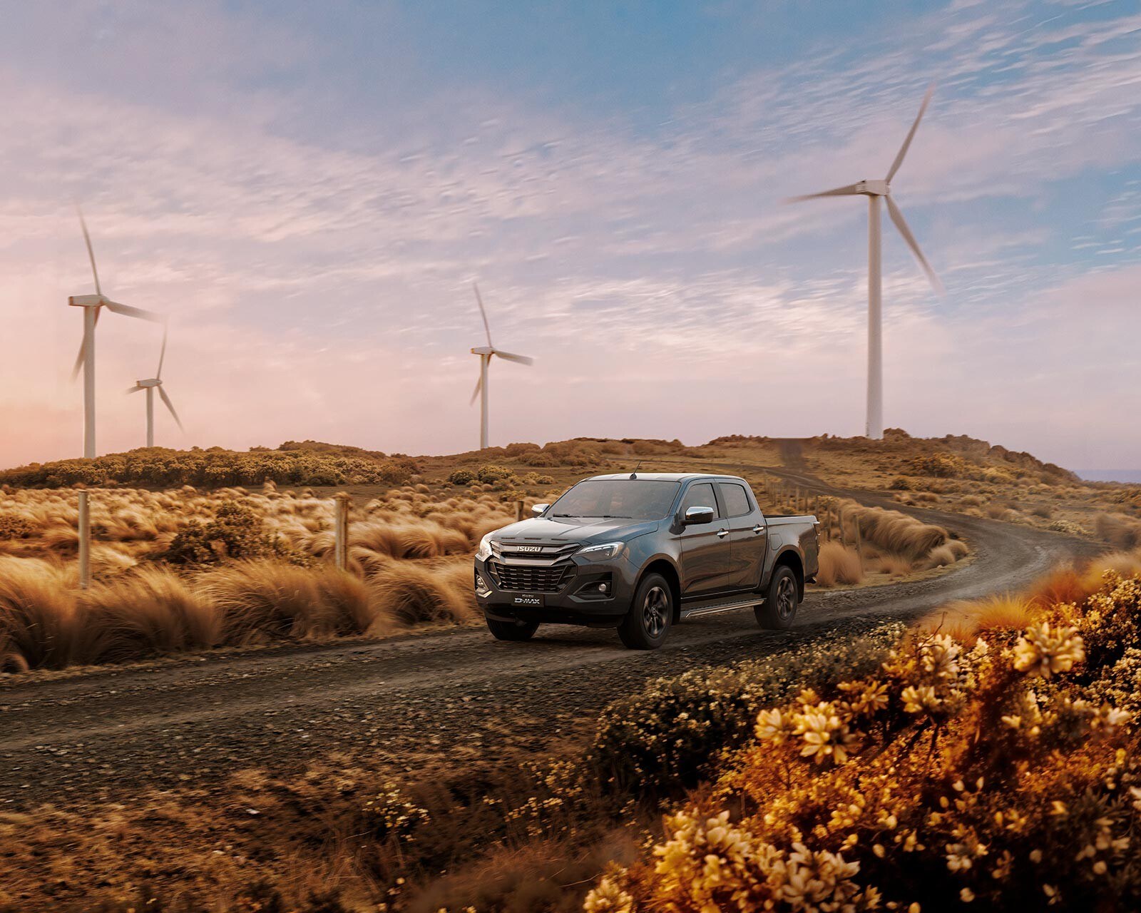 Isuzu D-Max sur une piste au pied des éoliennes